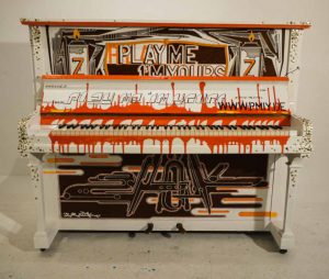 weiss getünchtes Klavier mit braun -oranger grafischer Bemalung und messing Ziernägeln