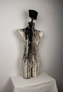 skulptur torso weiß mit schwarzem Pinsel als kopf übergossen von schwarzer Farbe die herrunterläuft